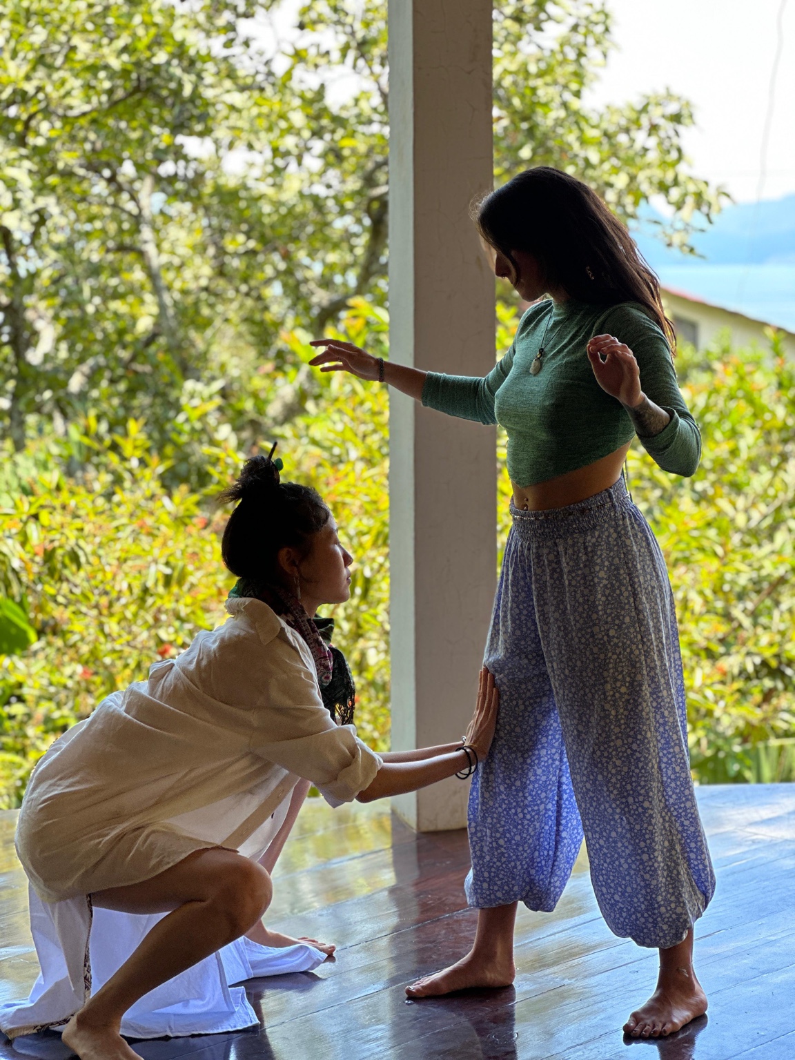 Megan kneeling in a hands-on moment of contact with another person, outdoors.